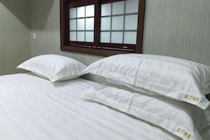 A room with two beds, each with white bedding and pillows, a window with a wooden frame, and a light switch on the wall. - Dandong Yading Hotel (Dandong)