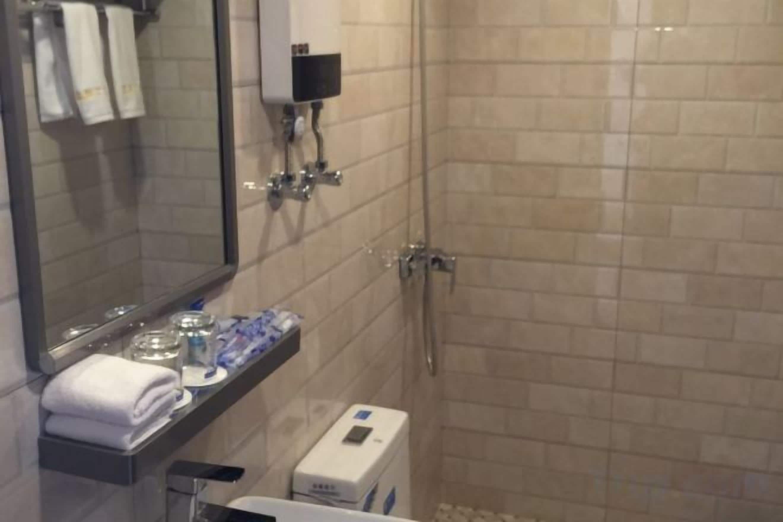 Un baño con espejo, lavamanos, toallero y ducha.
