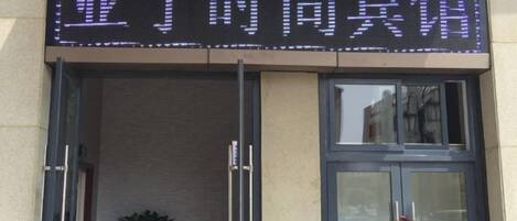 Ein Hotel Eingang mit einer digitalen Anzeige, die chinesische Schriftzeichen zeigt.