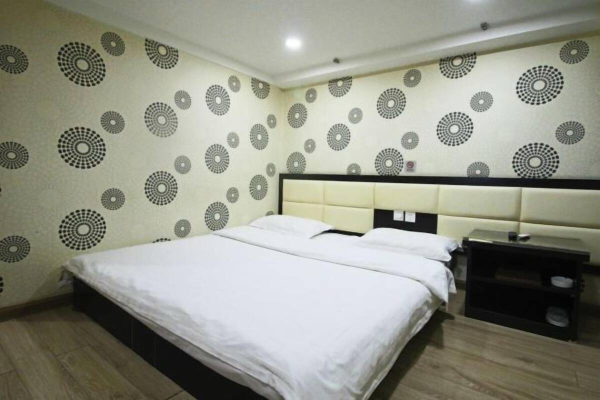 A hotel room with a bed, a nightstand, and a wall with circular patterns.