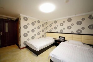 A hotel room with two beds, a nightstand, a wall with a circular pattern, and a door.