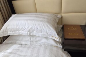 A bed with white striped bedding, a brown book on a nightstand, and a beige headboard.