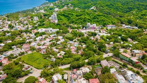 Une vue aérienne d’une ville côtière, caractérisée par une végétation luxuriante, une diversité de styles architecturaux et une vue dégagée sur l’océan.