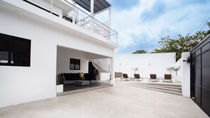 Une maison moderne dotée d’un vaste patio, d’un escalier menant à un deuxième étage et d’un espace salon extérieur.