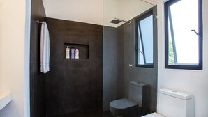 Une salle de bain moderne avec une douche à l’italienne, des toilettes et une fenêtre.