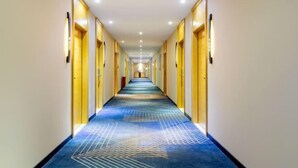 A long, narrow hotel corridor with doors on both sides, a patterned carpet, and recessed lighting on the ceiling. - Guangzhou Manya Fashion Hotel (Guangzhou)