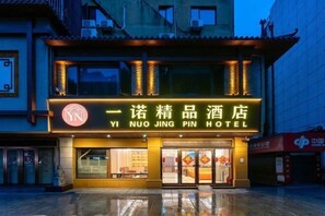 A hotel with a traditional architectural style, featuring a prominent sign with Chinese characters and a logo.