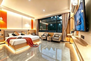 Una habitación de hotel moderna con una cama grande, televisión, zona de estar y un amplio ventanal.