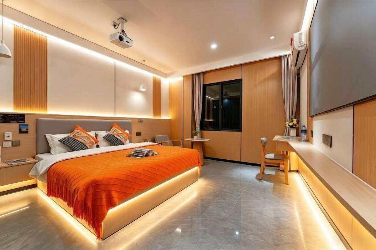A modern hotel room with a large bed, bedside tables, a desk, and a TV.