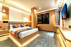 Un dormitorio moderno con una cama grande, mesitas de noche, un televisor y un ventanal con cortinas.