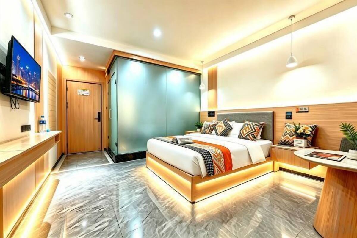 A modern hotel room with a large bed, a desk, a television, and a wardrobe.