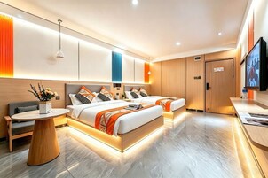 Una habitación de hotel moderna con dos camas, un escritorio, un televisor y una pequeña mesa con flores.