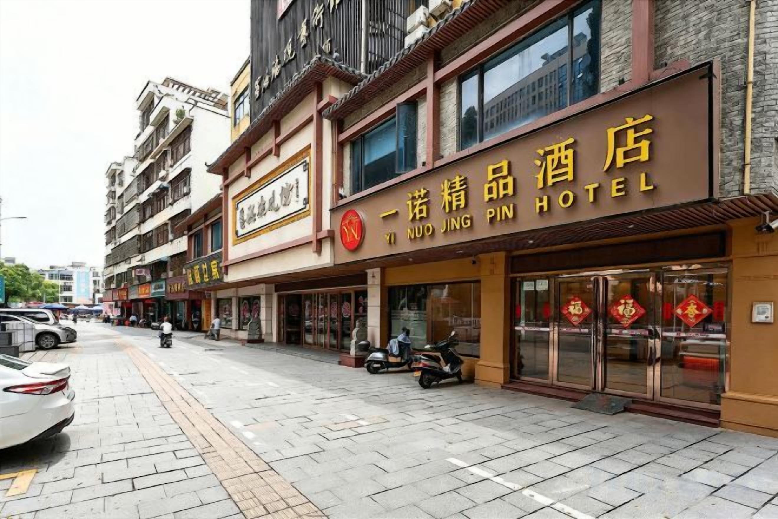 A hotel with a signboard, multiple floors, and a paved street in front.