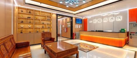 A hotel lobby with a reception desk, seating area, and a wall of trophies.