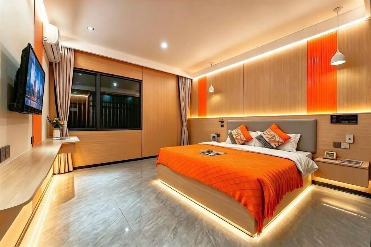 A modern hotel room with a large bed, a TV, a desk, and a window.