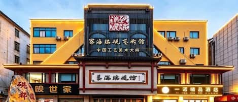 A hotel with a prominent signboard, multiple windows, and a reflective ground.