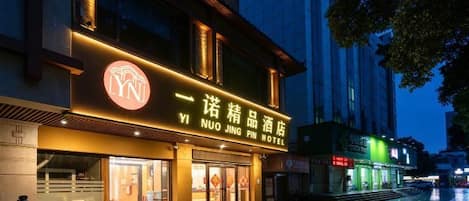 A hotel with a prominent sign, a well-lit entrance, and a visible outdoor area.