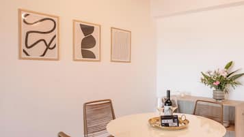 A dining area with a round table, wicker chairs, and abstract art on the wall.