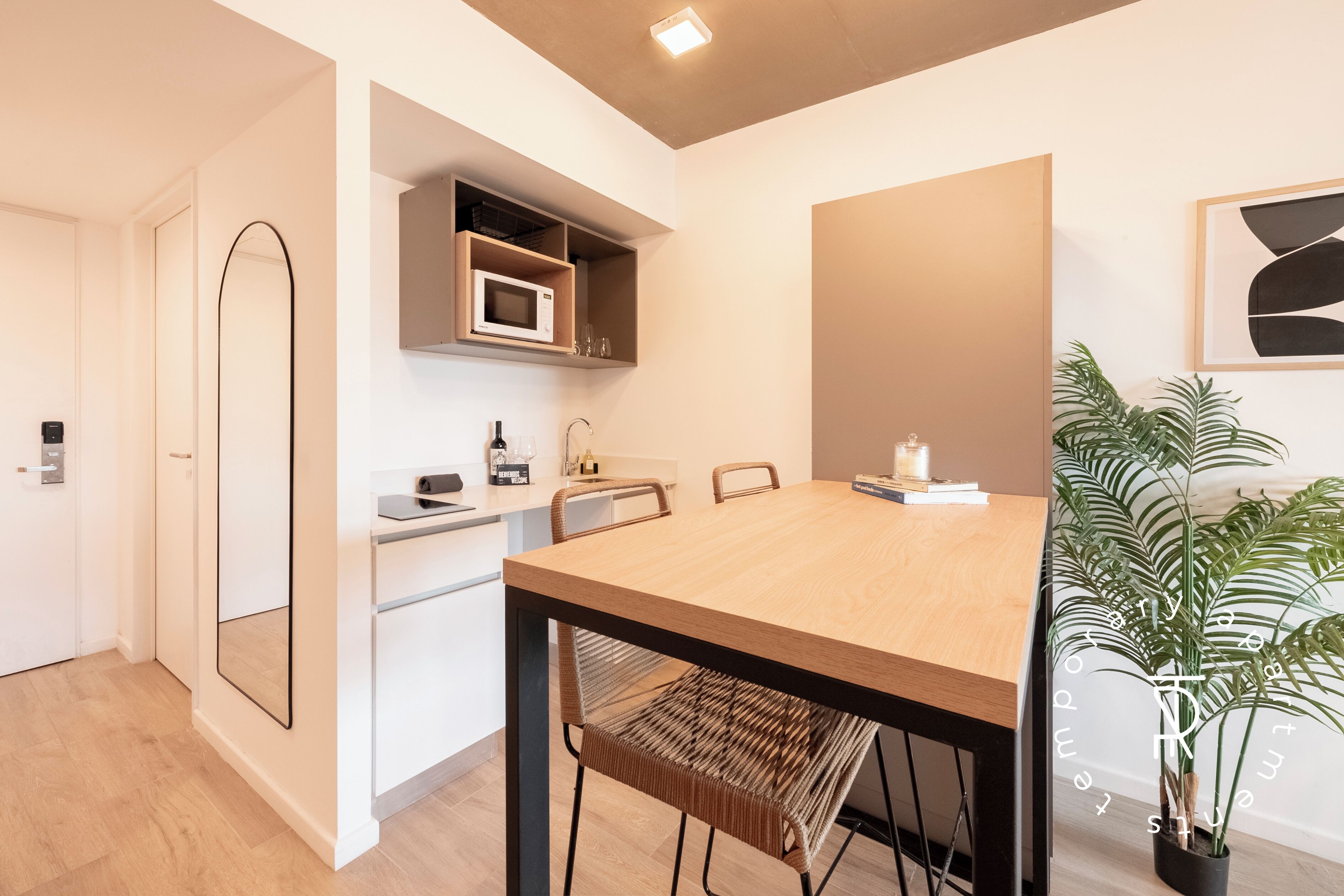 A modern kitchen with a microwave, wooden cabinets, and a dining table with chairs.