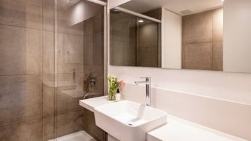 Un bagno moderno con uno specchio grande, un lavandino bianco e una zona doccia.