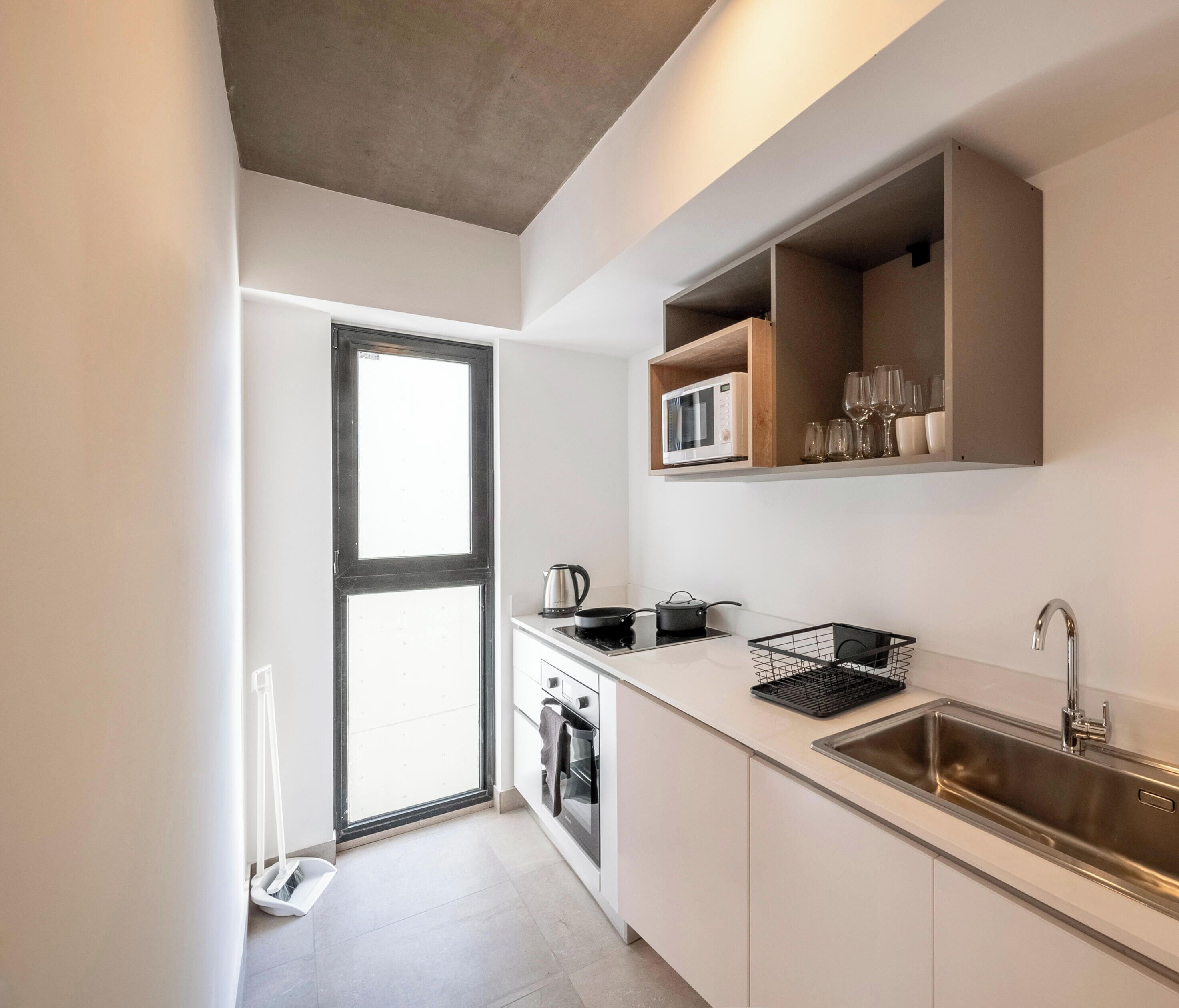 A modern kitchen with a built-in microwave, a stainless steel sink, and a window.