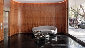 A modern lobby with a curved wooden wall, a white sofa, and a glass coffee table. - Top Rentals Nuñez (Buenos Aires)