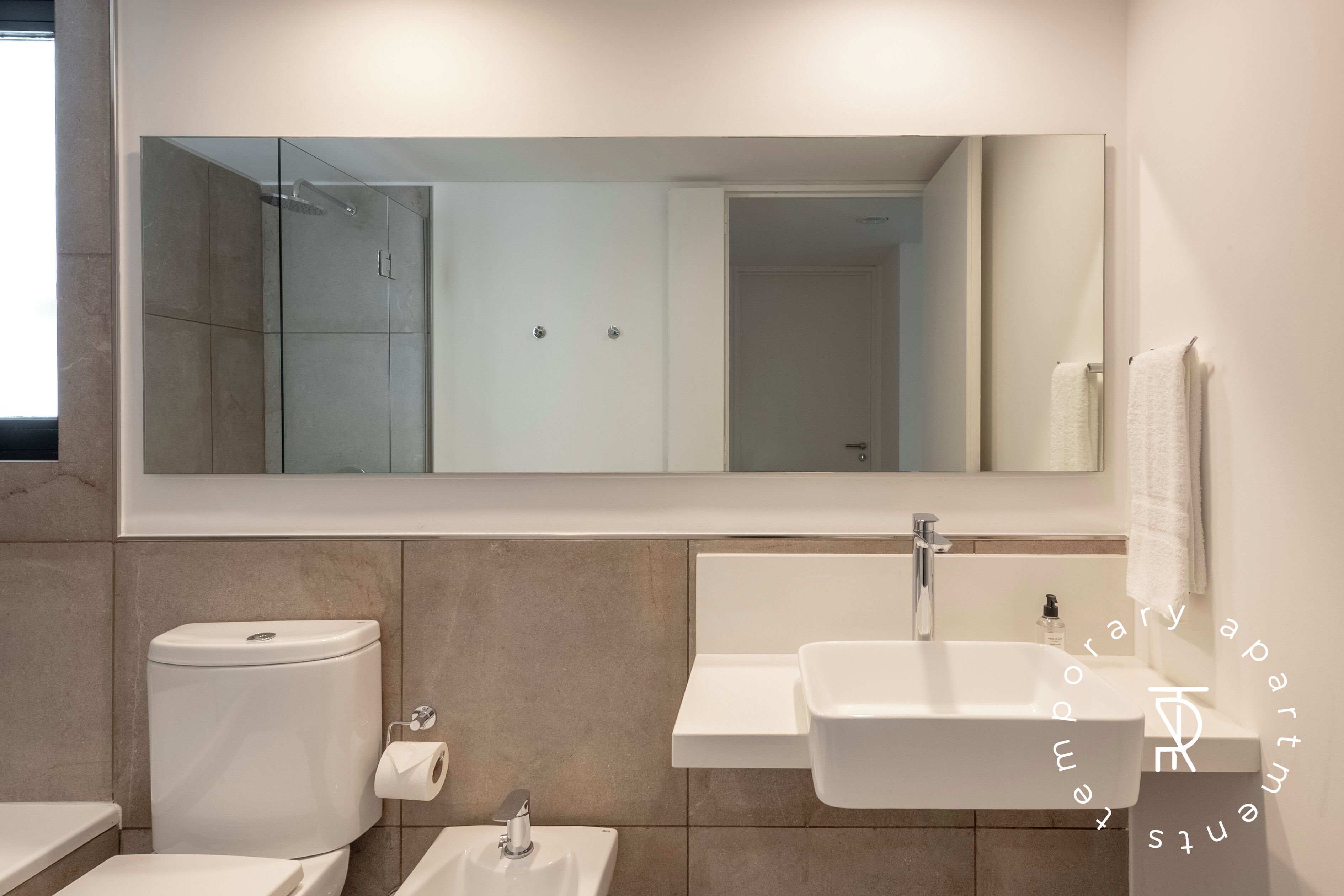 A modern bathroom with a toilet, sink, and shower.