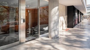 A modern hotel lobby with glass doors, a reception desk, and a large pillar. - Top Rentals Nuñez (Buenos Aires)