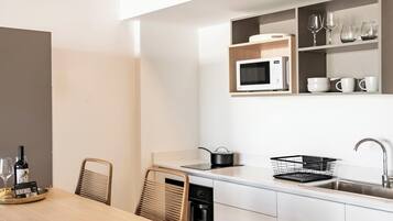 Una cocina moderna con armarios blancos, un microondas, un fregadero y una zona de comedor con mesa y sillas.