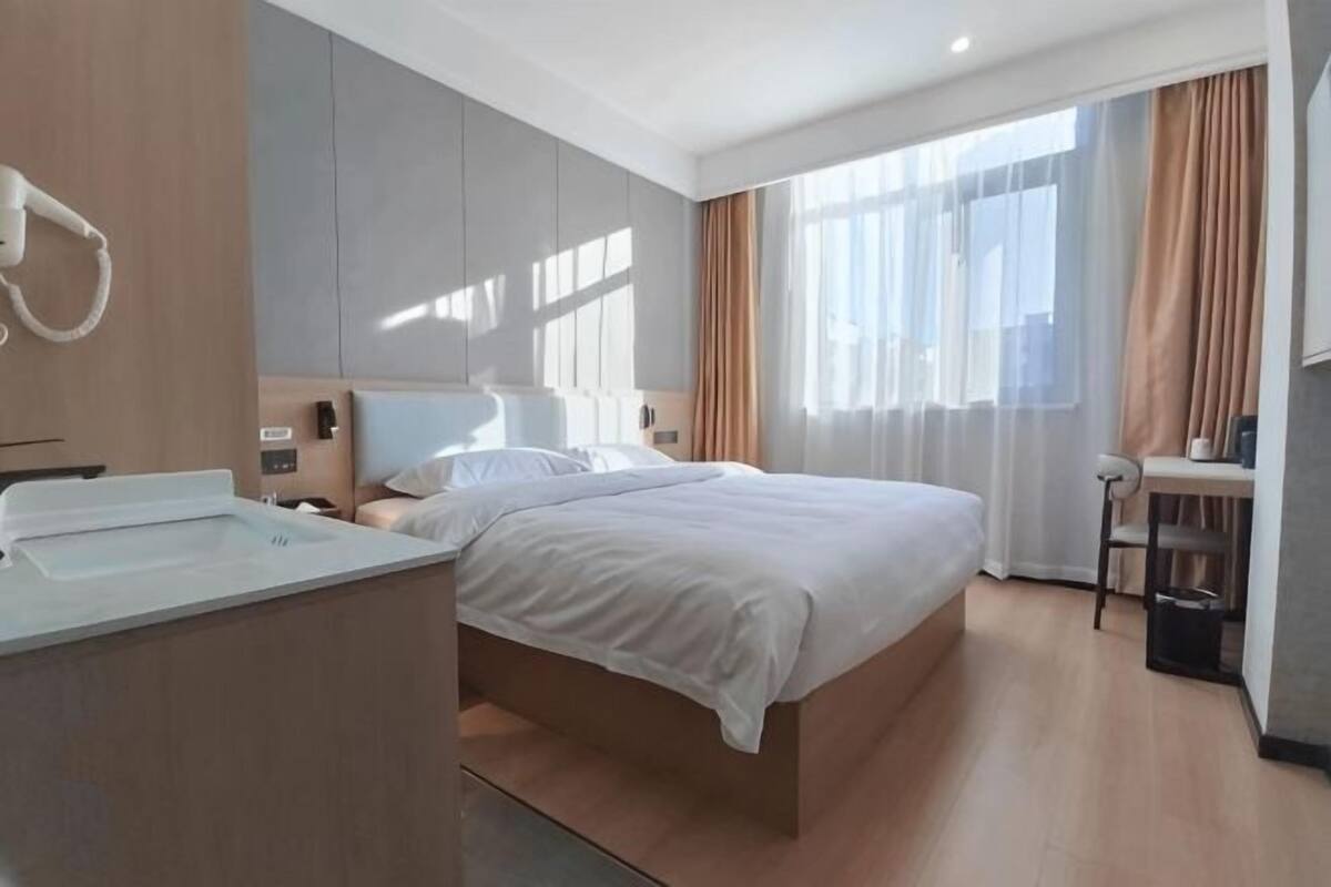 Una habitación de hotel moderna con una cama grande, un escritorio y un baño.