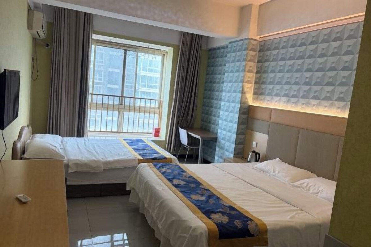 Une chambre d’hôtel avec deux lits, un bureau et une fenêtre avec des rideaux.