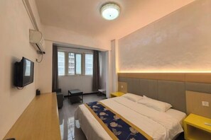 Ett hotellrum med en säng, ett nattduksbord, en tv och ett skrivbord.