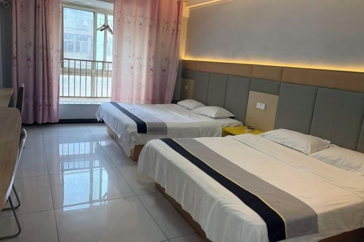 Une chambre d’hôtel avec deux lits, un bureau et une fenêtre avec des rideaux.