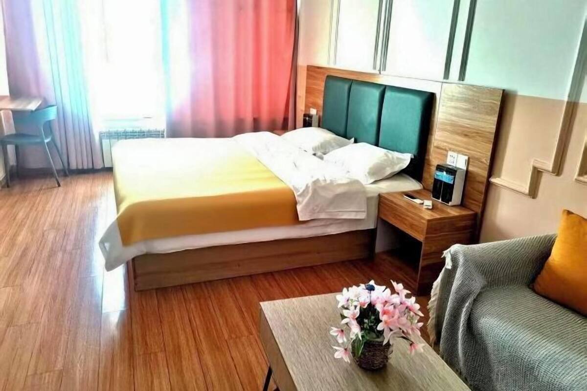 Una habitación de hotel con una cama, mesita de noche y una pequeña mesa con flores.