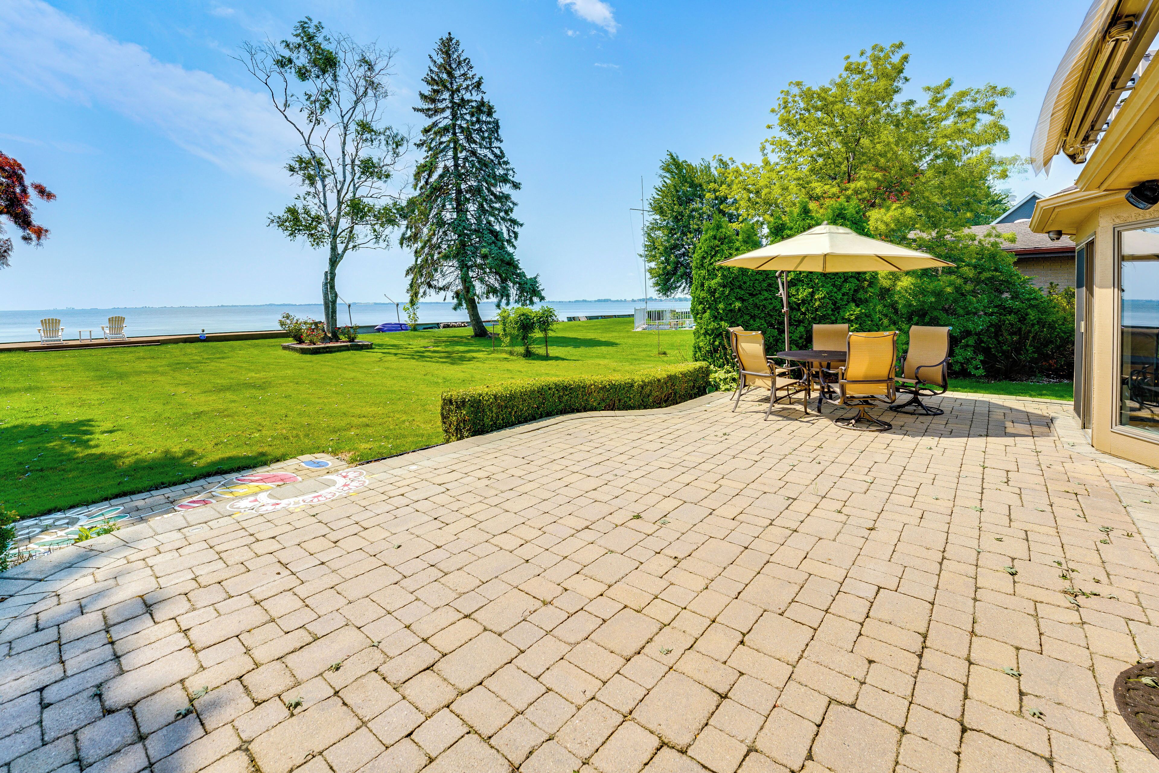 Un patio con suelo de ladrillo, mobiliario exterior y vista al agua.