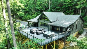 A cabin with a deck, hot tub, and outdoor seating area surrounded by forest. - Luxe Smoky Mountains Cabin w/ Hot Tub & Views! (Waynesville)