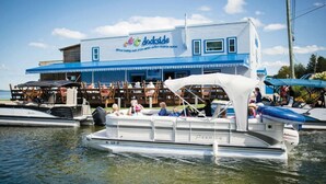 A docked boat in front of a building with a blue and white exterior, featuring a sign that reads "dockside." - Torch lake waterfront:100 ft of sandy beach, 3-bedroom, 3-bath cottage (Alden)