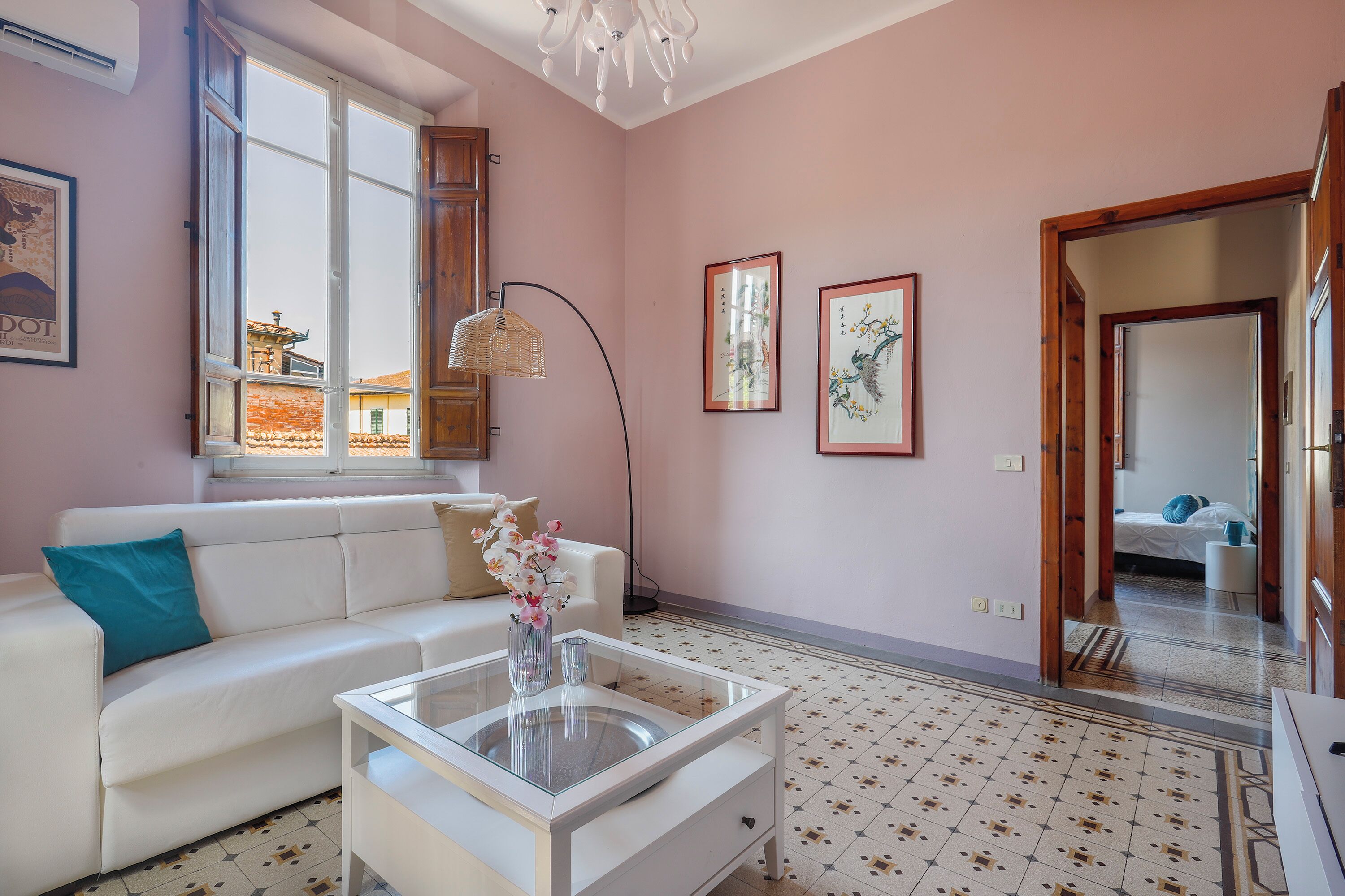 Un salon moderne avec un canapé blanc, une table basse en verre et une grande fenêtre.