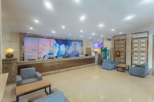 A hotel lobby with a reception desk, seating area, and a large wall mural.