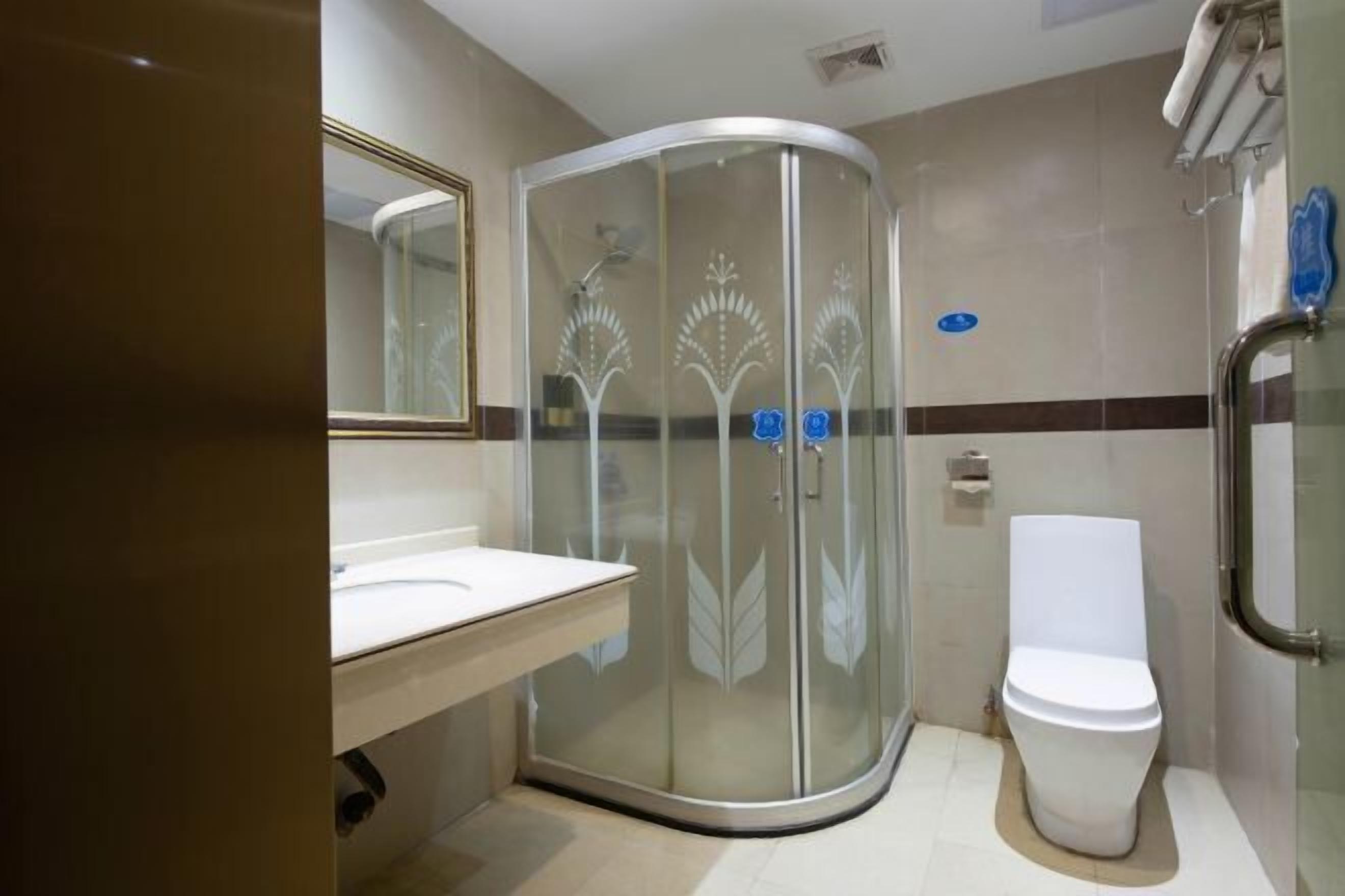 A modern bathroom with a glass shower enclosure, a toilet, and a vanity with a mirror.