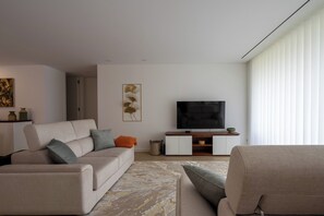 Relax in this stylish living room with a beige sofa, armchair, and flat-screen TV.