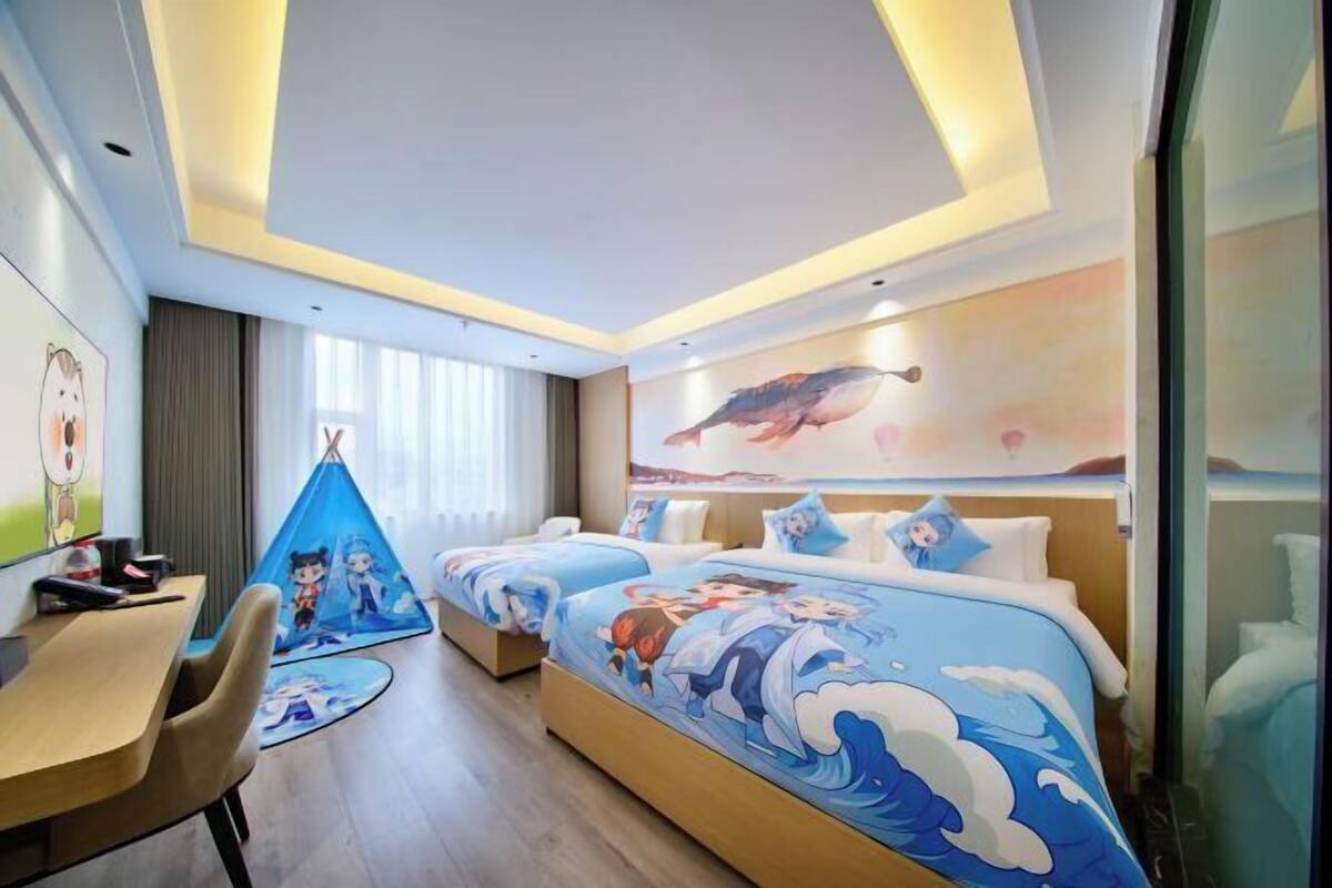 A hotel room with two beds, a desk, and a chair.