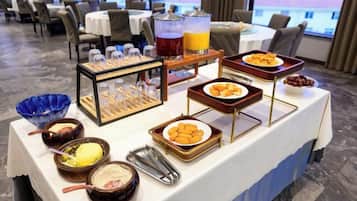 A buffet table with various food items and a fruit punch dispenser.