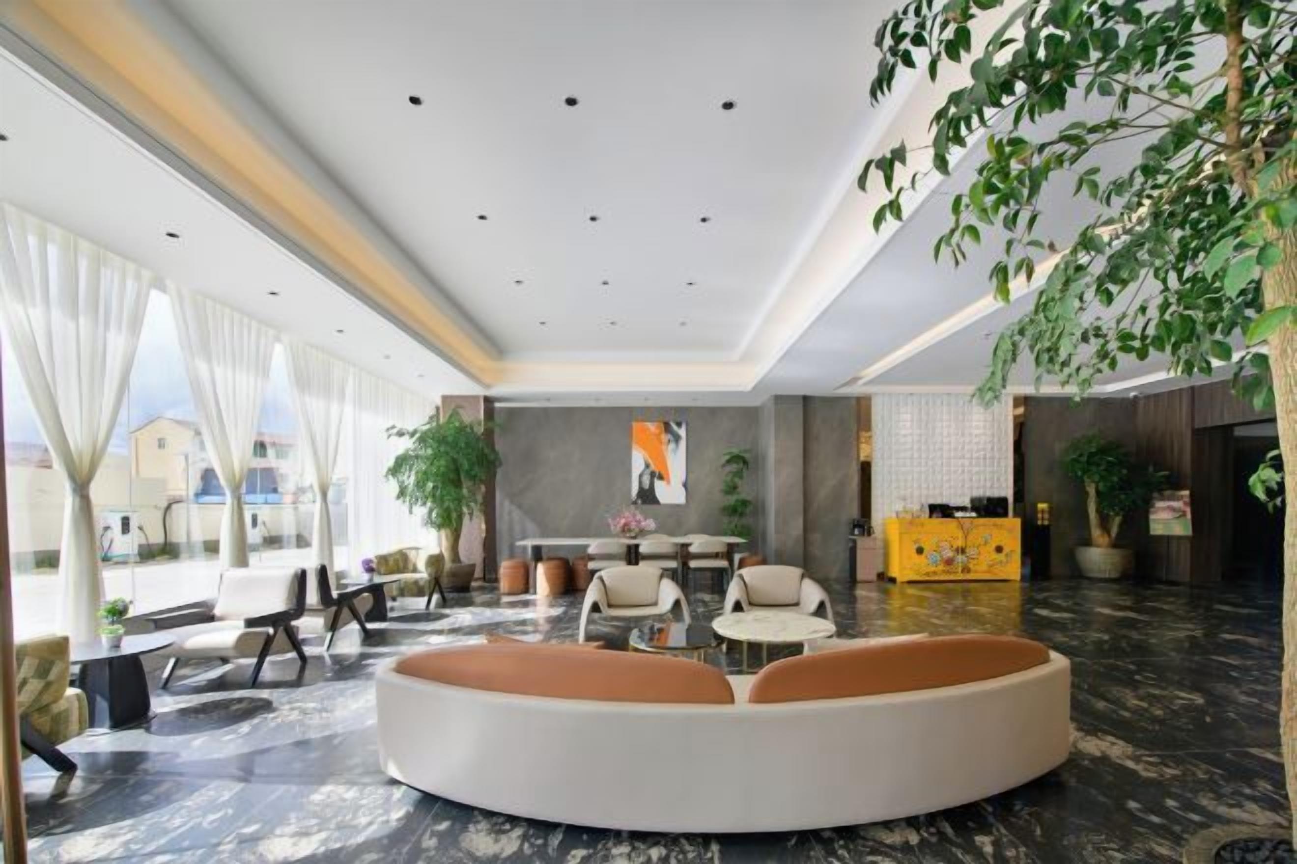 Een moderne hotellobby met een gebogen zithoek, een receptiebalie en een groot raam met uitzicht op het omliggende landschap.