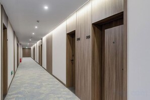 A hotel corridor with wooden doors, numbered 302 and 303, and a patterned carpet. - Coffey Hotel (Hongyuan)