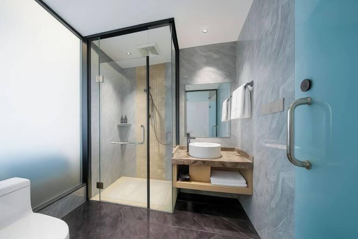 A modern bathroom with a glass-enclosed shower, a white sink, and a blue accent wall.