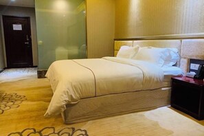 A hotel room with a large bed, a bedside table, and a door. - Coffey Hotel (Hongyuan)