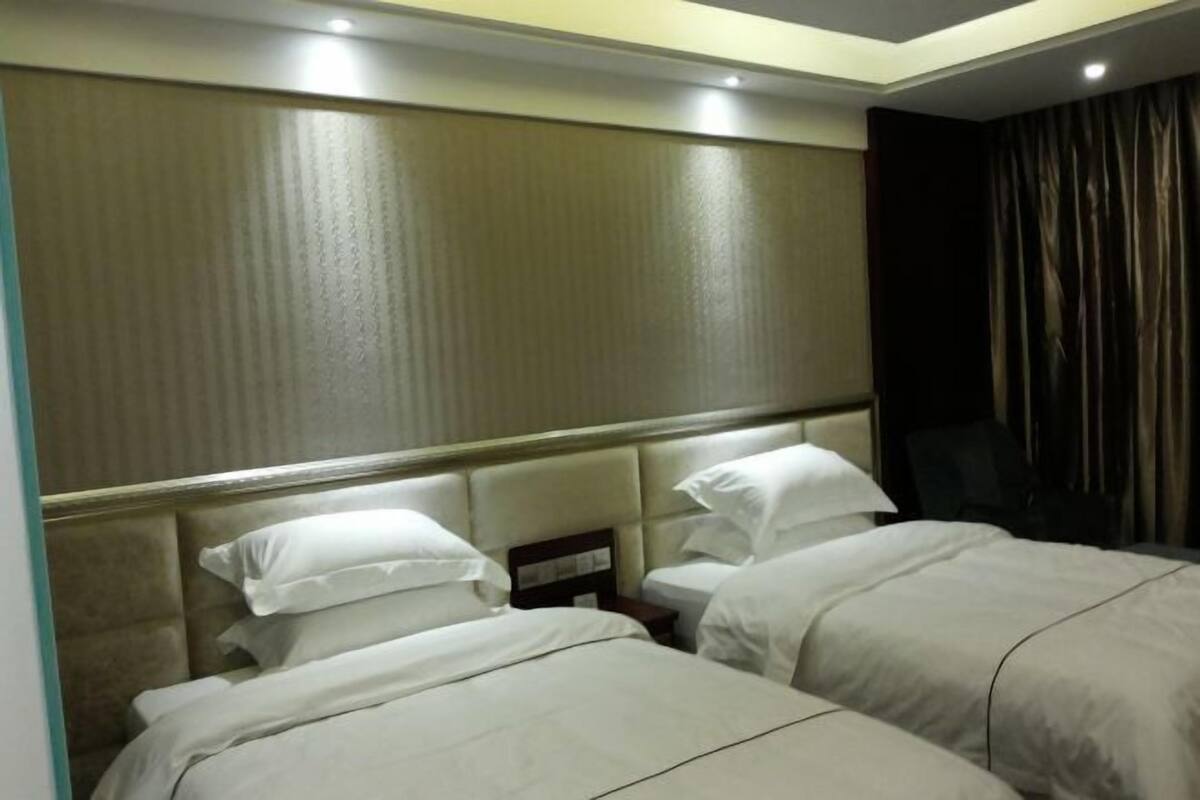 A hotel room with two beds, a headboard, and a curtain.