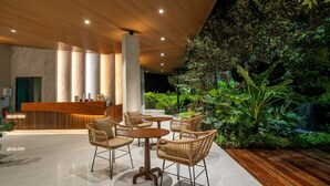 A reception area with a wooden reception desk, wicker chairs, and a lush indoor garden. - Timberton Resort Khaoyai (Pak Chong)