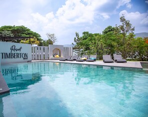 Une piscine avec des chaises longues et un mur sur lequel est inscrit le nom « Resort TIMBERTON ».